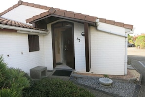 A small building with a white exterior, a brown roof, and a number '83' on the wall.