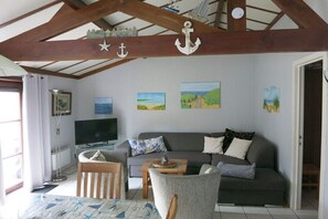 A living room with a sofa, chairs, a television, and artwork on the walls. - Holiday apartment with 2 bedrooms (Bredene)