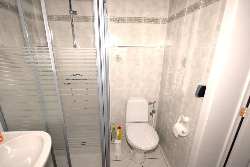 A bathroom with a glass shower enclosure, a toilet, and a sink.