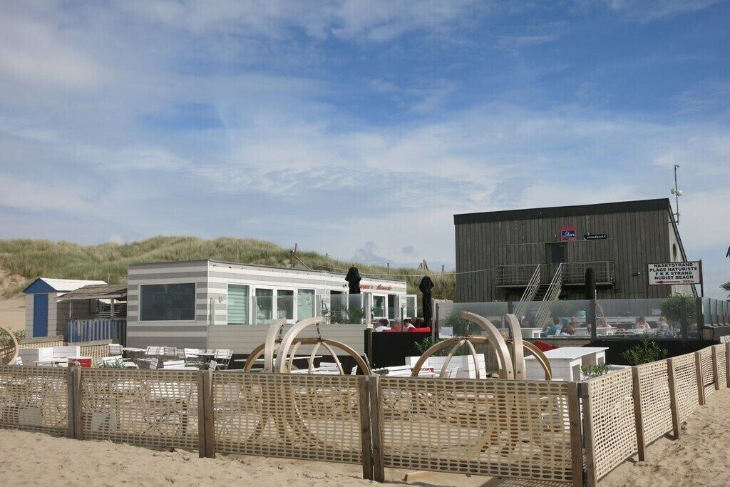 A beachside caravan park with multiple caravans and a large building with a sign indicating a place for naturist activities.