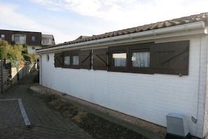 Ein weißes Gebäude mit einem Ziegeldach und Holzklappläden an den Fenstern.