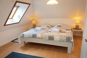Een slaapkamer met een bed, twee bedlampen, een raam en een plafondlamp.