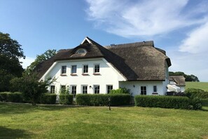A large white building with a steeply pitched roof, surrounded by a well-maintained lawn and hedges. - favorite spot in the thatched house (Putbus OT Wreechen)