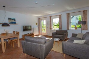 A living room with a sofa, armchair, TV, and dining table. - favorite spot in the thatched house (Putbus OT Wreechen)