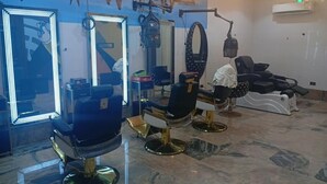 Un salón de barbería con dos sillones de peluquería, espejos y un secador en la barra.