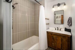 Ein Badezimmer mit Dusche, Badewanne, Waschtisch und Spiegel sowie einem Handtuchhalter.