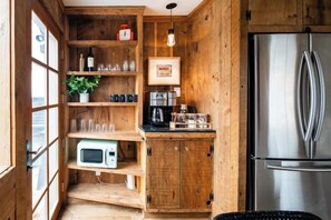 A compact kitchen with wooden cabinetry, a stainless steel refrigerator, a microwave, and a coffee maker. - Downtown Bungalow- Modern Bungalow in the heart of Downtown Bozeman (Bozeman)