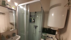 Ein Badezimmer mit Duschkabine, Waschbecken und Spiegel.
