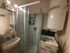 Een badkamer met een douchecabine van glas, een wastafel en een spiegel.