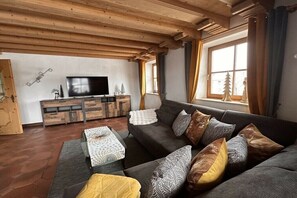 Uma sala de estar com sofá, mesa de centro e televisão.
