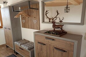 Ein Zimmer mit einem Holzschrank, einer Bank, einem Spiegel und einer Hirschfigur.