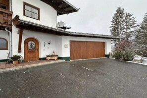 Ein zweigeschossiges Gebäude mit einer großen Garagentür, einer Satellitenschüssel und einer verschneiten Landschaft.