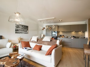 A modern living room with a sofa, coffee table, and dining area. - Bright apartment with pool - ski-in/ski-out (Huez)