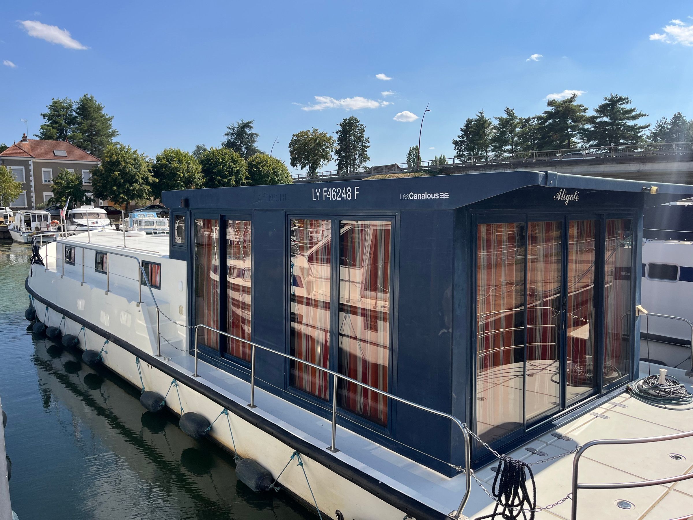 Een stilgelegen boot met een afgedekt dek, een zichtbare hut en een verankeringssysteem.