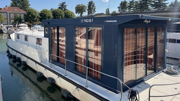 Een stilgelegen boot met een afgedekt dek, een zichtbare hut en een verankeringssysteem.