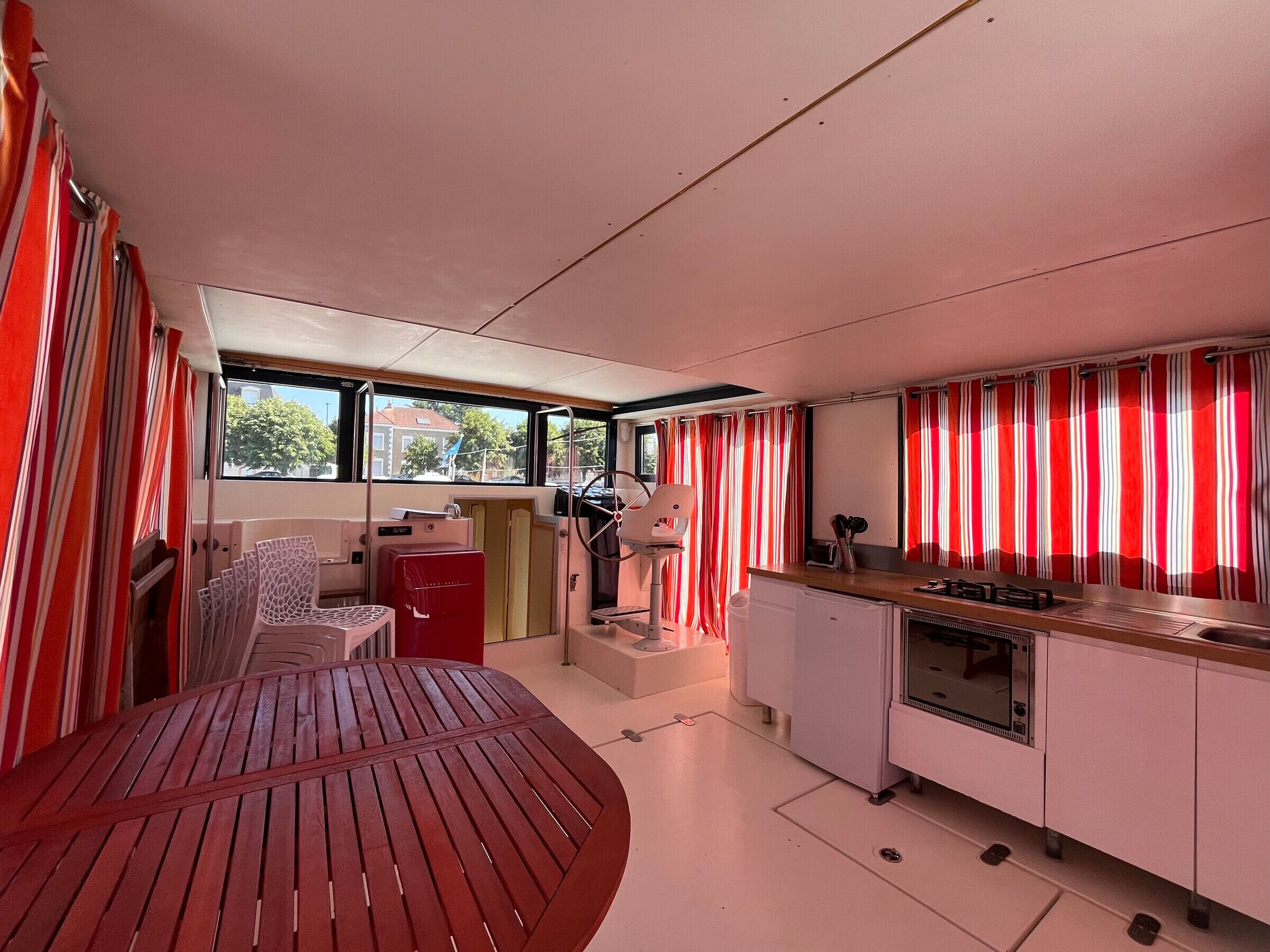 Een compact keuken met een eethoek, een rode tafel en uitzicht door de ramen.