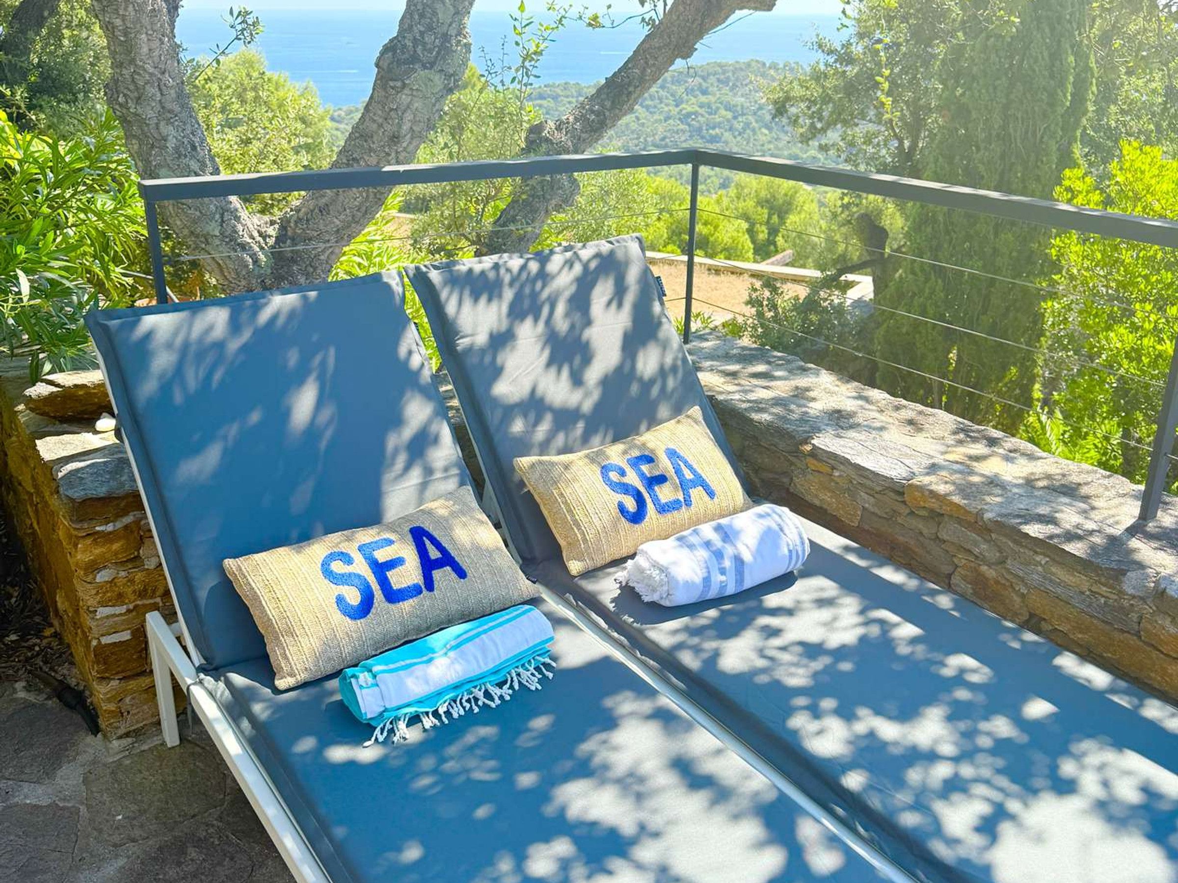 A sunlit outdoor seating area with two lounge chairs, each with a cushion labeled 'SEA.'