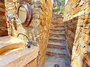 Un baño con paredes de piedra, un lavamanos y un espejo.