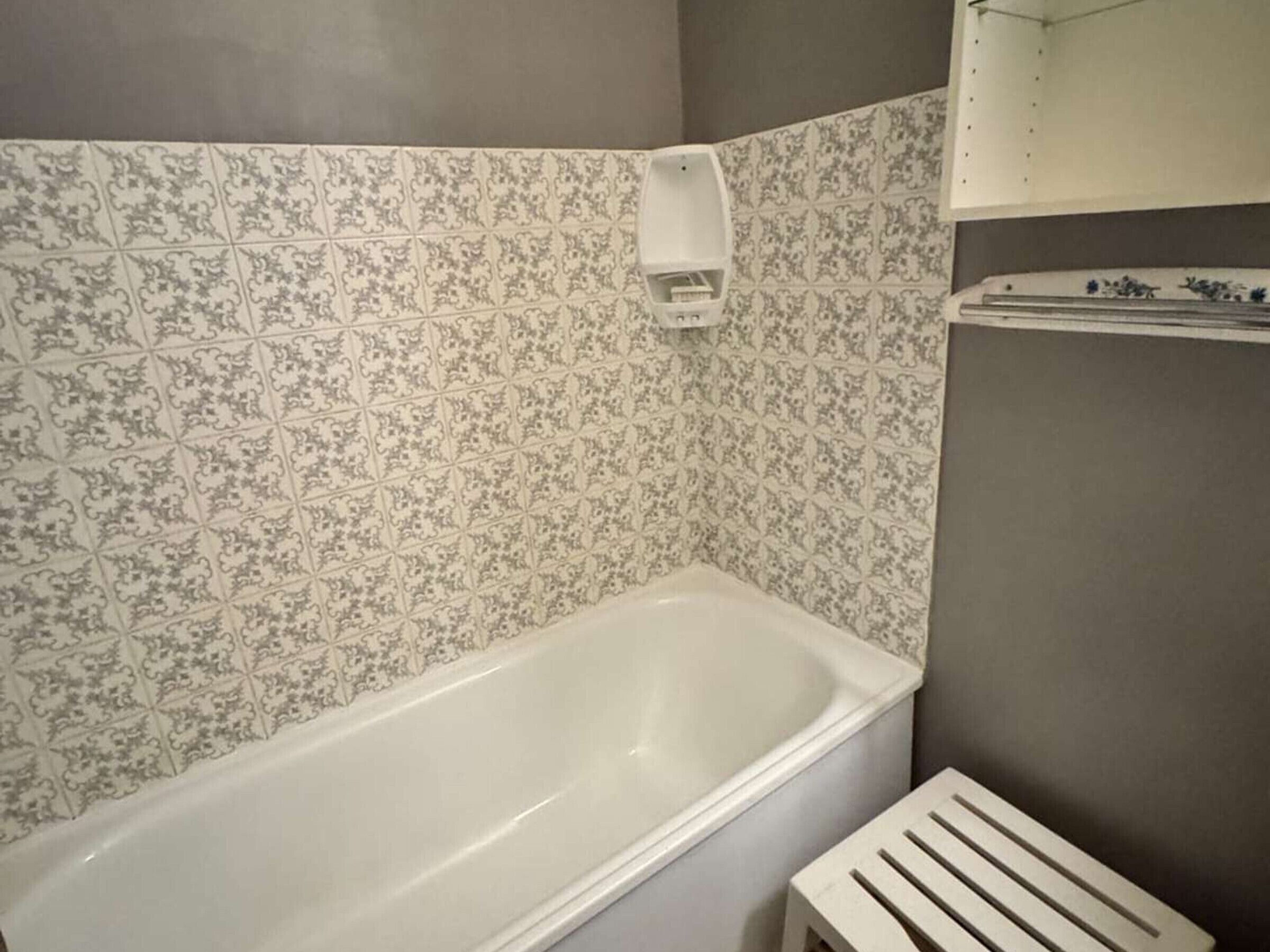 Een badkamer met een wit bad, betegelde wanden en een handdoekhouder.