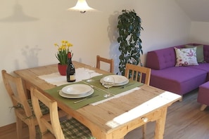 Ein Esstisch mit Stühlen, ein Blumentopf und ein violettes Sofa in einem Zimmer.