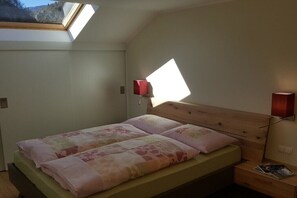 Ein Schlafzimmer mit Dachfenster, einem Bett mit floralem Bettzeug und zwei Wandlampen.
