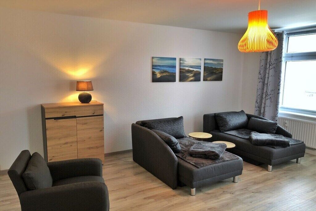 Een moderne woonkamer met twee banken, een bijzettafeltje en een kast. Drie ingekaderde foto's hangen aan de muur.