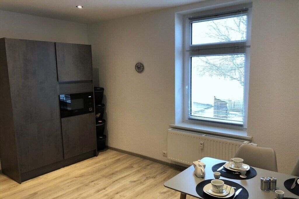 Cocina compacta con horno empotrado y comedor con mesa dispuesta para dos.