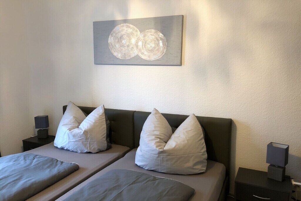 Une chambre d’hôtel avec un lit, deux tables de chevet et une œuvre d’art accrochée au mur.