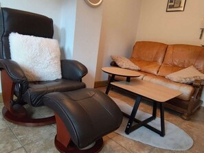 A living room with a leather armchair, a sofa, and a small table. - Apartment with parking in city center - 3 guests (Amélie-les-Bains-Palalda)