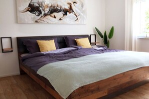 A bed with a wooden frame, a headboard, and multiple pillows in purple and yellow. - Holiday apartment with 1 bedroom (Frickingen)