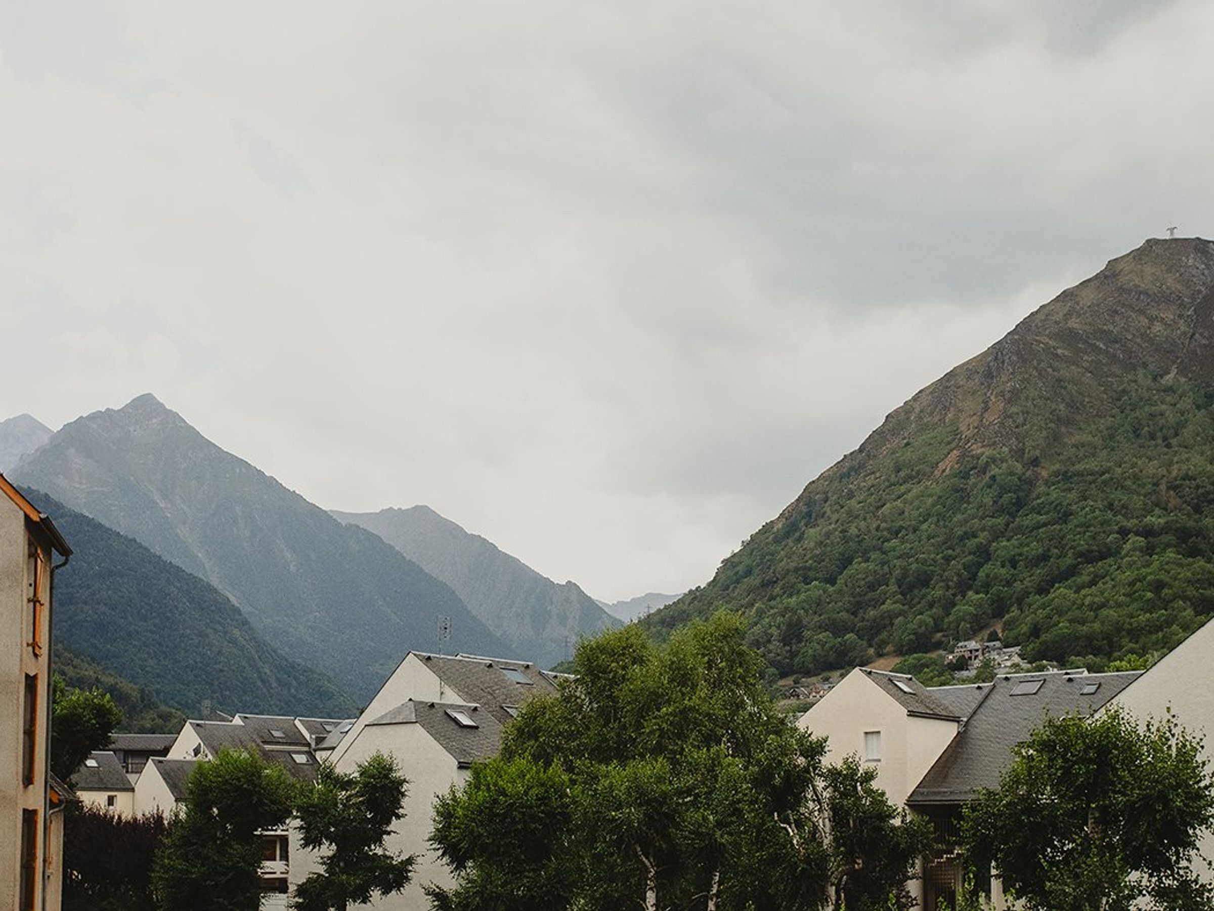 A residential area with houses, a mountain in the background, and a cloudy sky.