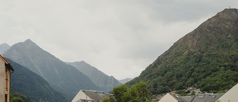 A residential area with houses, a mountain in the background, and a cloudy sky.