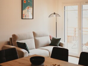 A living room with a sofa, a dining table, and a floor lamp. - Duplex apartment with parking - 5 guests (Saint-Lary-Soulan)