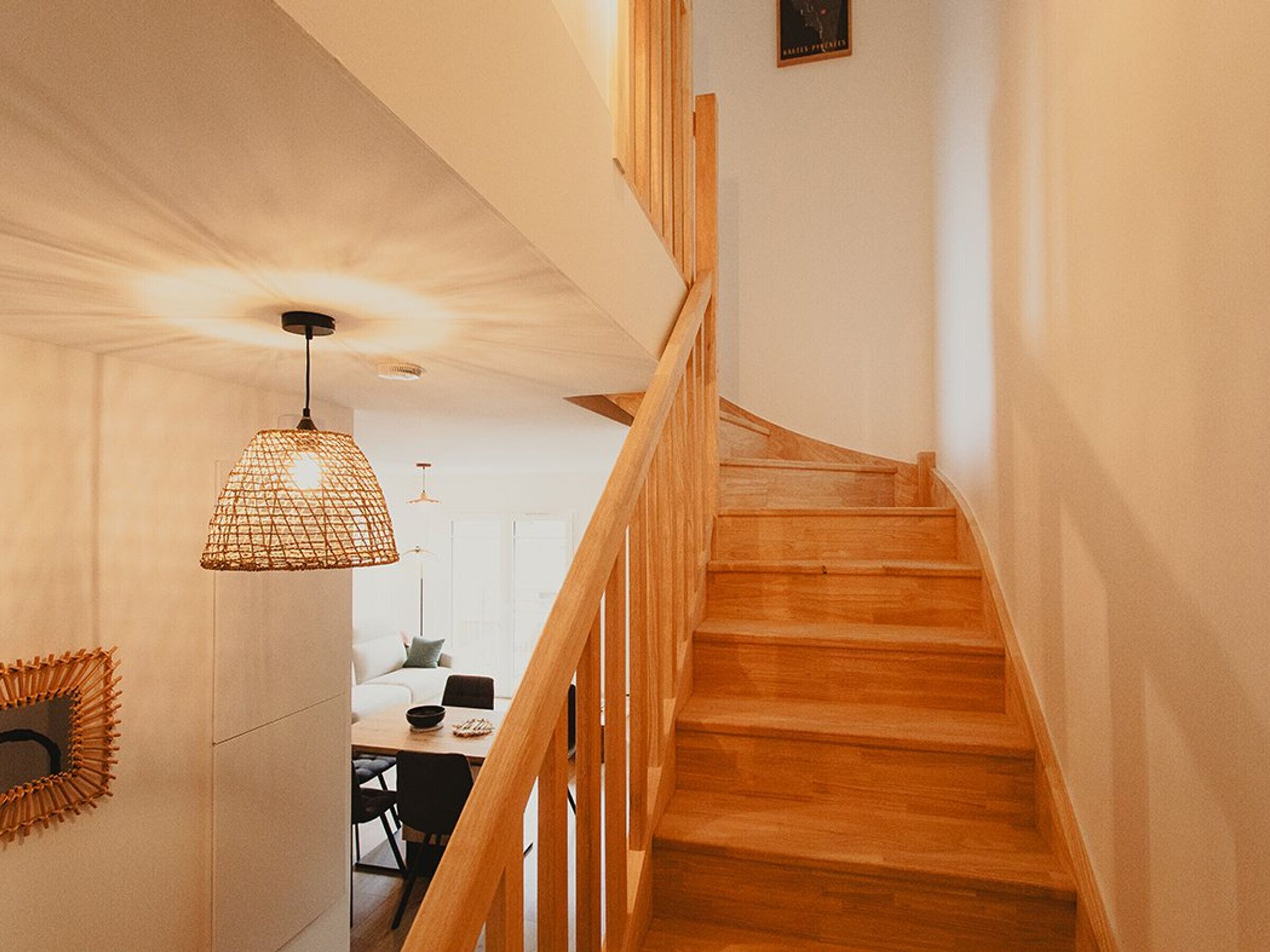 A wooden staircase leading to a dining area with a hanging light fixture.