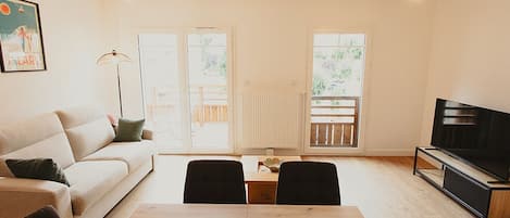 Una sala de estar moderna con sofá, mesa de comedor, sillas, televisor y chimenea.