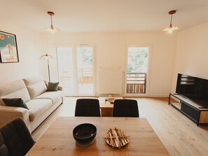 Un salon moderne comprenant un canapé, une table à manger, des chaises, un téléviseur et une cheminée.