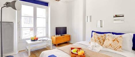 A modern bedroom with a bed, bedside table, TV, and a window with a view.