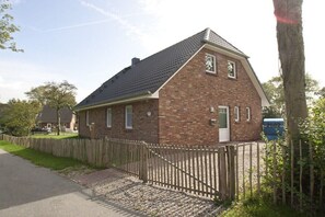 A brick house with a sloped roof, a wooden fence, and a mailbox. - Holiday home with 2 bedrooms (Dagebüll OT Süderwaygaard)