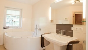 A modern bathroom with a freestanding bathtub, a sink, and a mirror. - Holiday home with 2 bedrooms (Dagebüll OT Süderwaygaard)