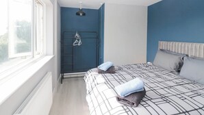 A bedroom with a bed, a radiator, a window, and a clothes drying rack. - Aqueduct Residence (Lancaster)