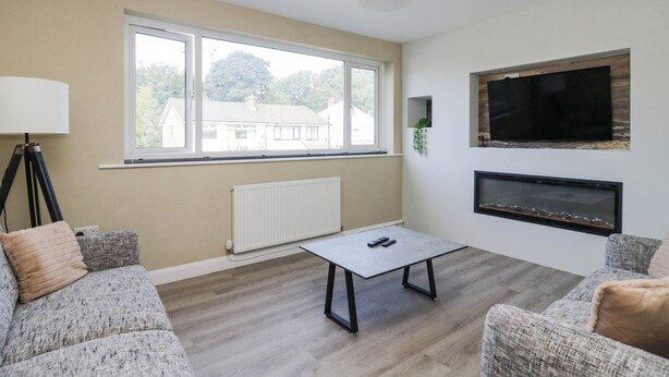 A living room with a sofa, a coffee table, a TV, and a fireplace. - Aqueduct Residence (Lancaster)