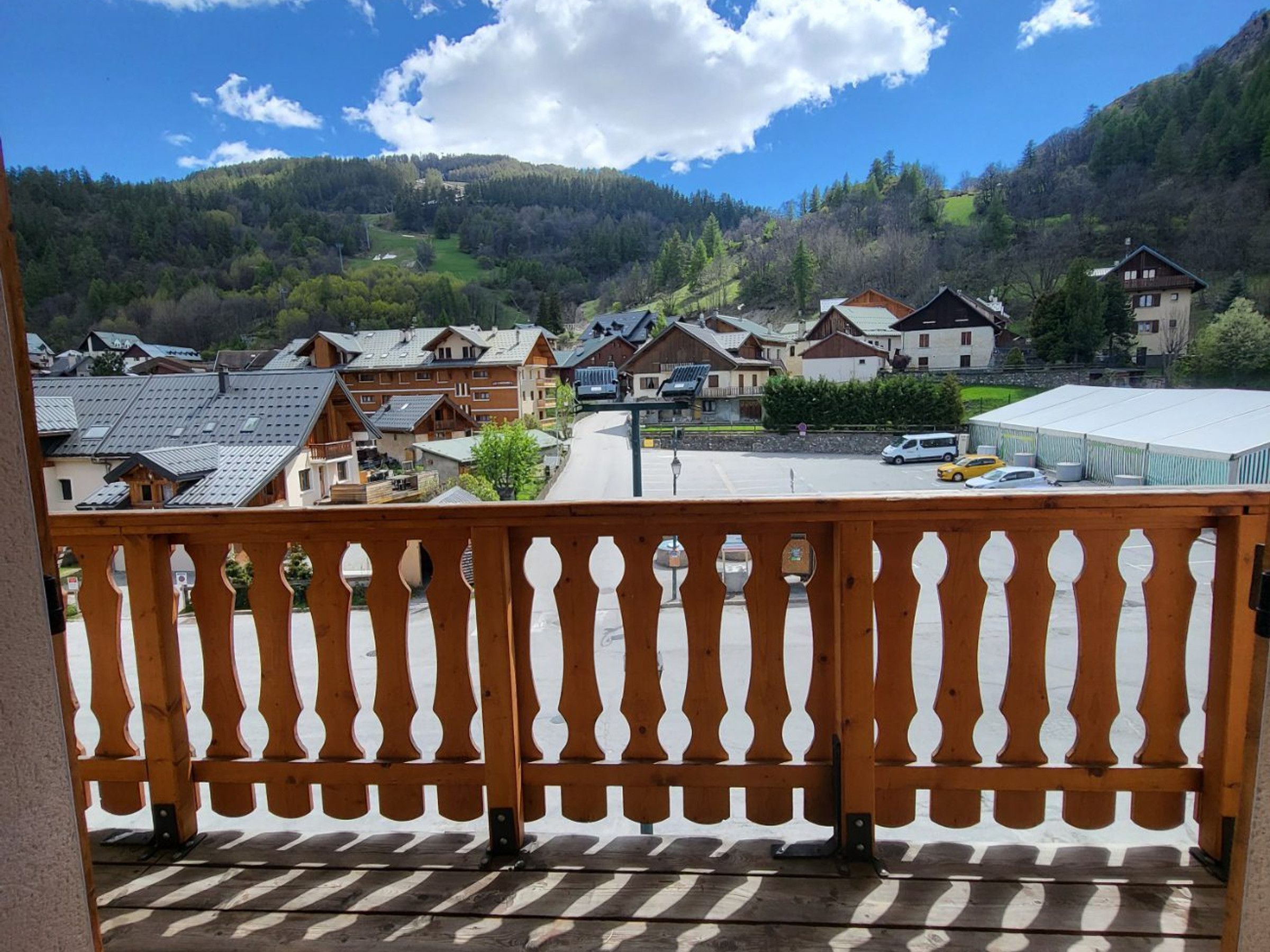 Un balcon donnant sur un quartier résidentiel, avec vue sur des maisons et un parking.