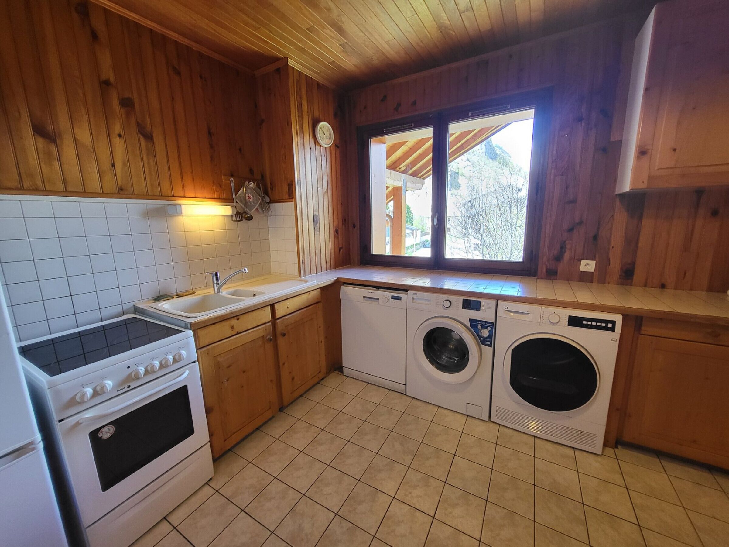 A compact kitchen with a stove, sink, and two washing machines.