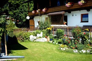 A traditional building with a wooden fence, a well-maintained garden with colorful flowers, and a clear view of the surrounding greenery. - in the Landfrieden House (Leutasch)