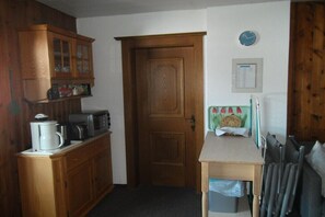 A compact kitchen with wooden cabinets, a microwave, and a coffee maker. - in the Landfrieden House (Leutasch)