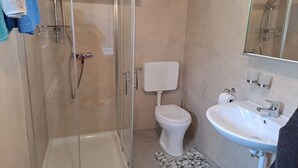 Een badkamer met een douchecabine, toilet en wastafel.