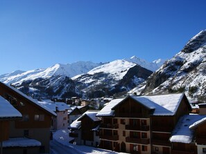 Ein verschneites Bergdorf mit Holzhäusern und blauem Himmel.