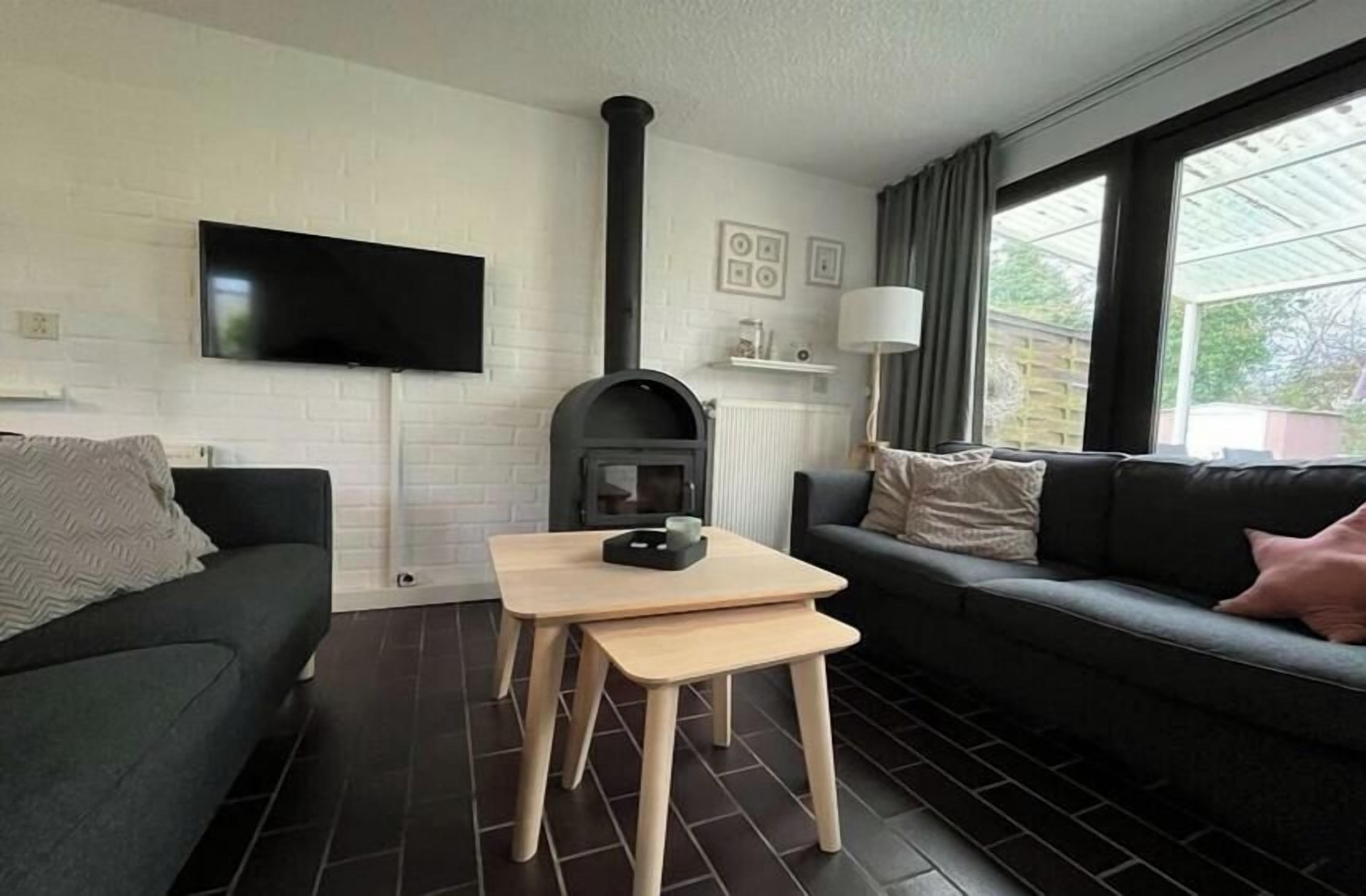 A modern living room with a fireplace, a flat-screen TV, and a sofa.