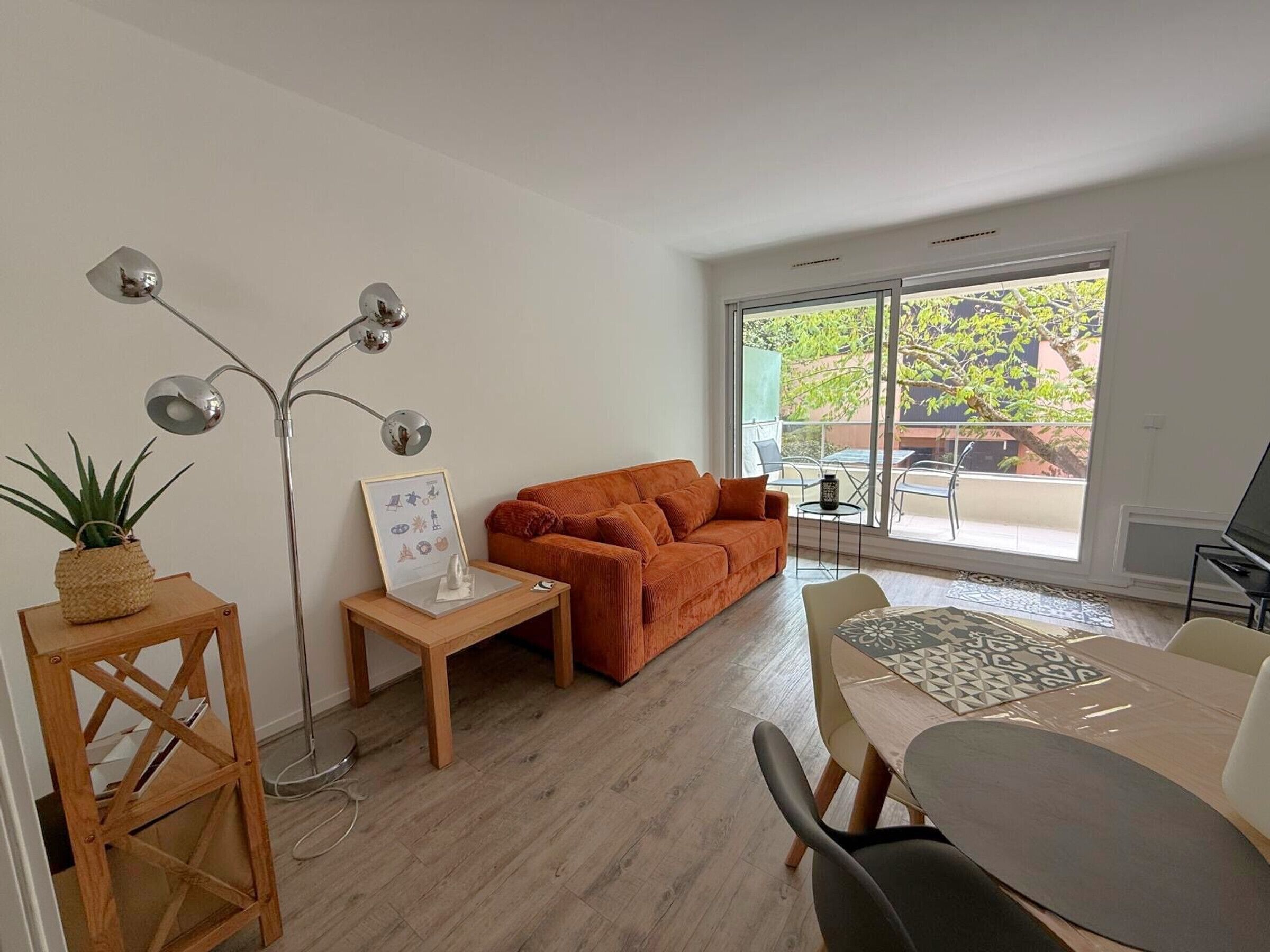 Ein modernes Wohnzimmer mit einer Couch, einem Esstisch und einem großen Fenster.
