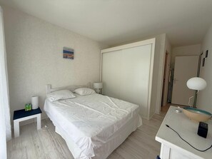 Ein Hotelzimmer mit Bett, Nachttisch, Lampe und einem kleinen Bild an der Wand.